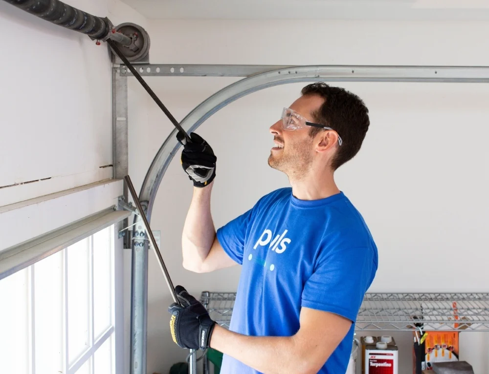 Technician adjusting the torsion spring on a sectional garage door